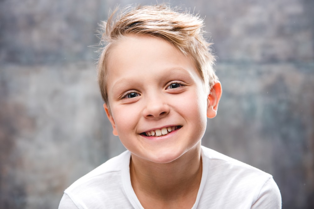 A smiling boy wearing a white shirt.